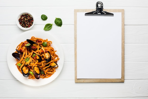 Gratis foto plat leggen van mosselen pasta met klembord