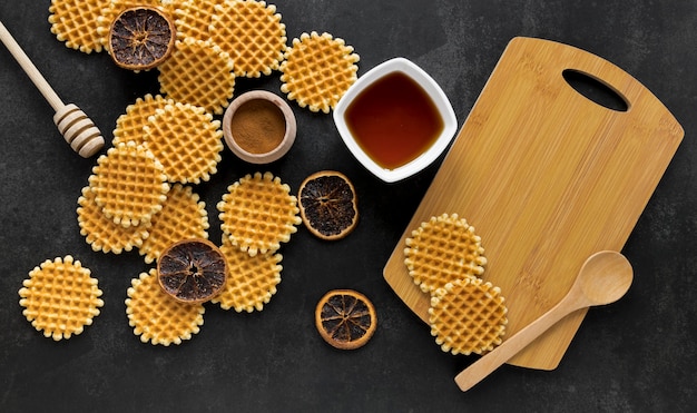 Gratis foto plat leggen van ronde wafels met honingdipper en gedroogde citrus