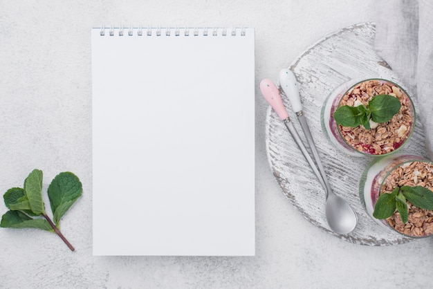 Gratis foto plat leggen van yoghurt glazen met granen en notebook