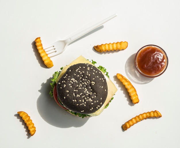 Gratis foto plat leggen van zwarte hamburger met friet