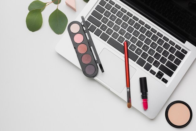 Platliggend arrangement met laptop en make-up palet