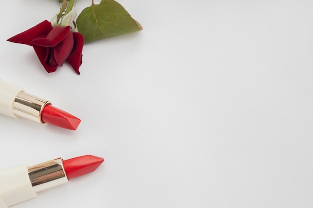 Platliggend kader met rode lippenstiften en roos