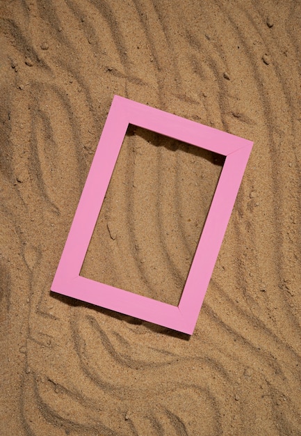 Gratis foto platliggend roze frame op zand