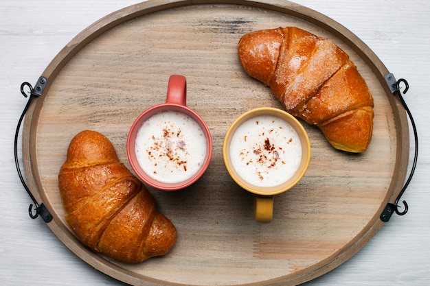 Gratis foto platliggende koffiekopjes met croissants