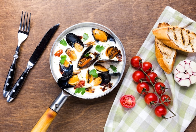 Platliggende mosselen in witte saus en zijden op tafelkleed