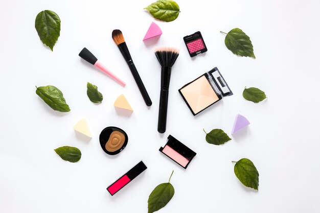 Poederborstels met cosmetica en groene bladeren