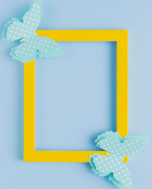Polka gestippelde vlinder op geel grenskader over blauwe achtergrond