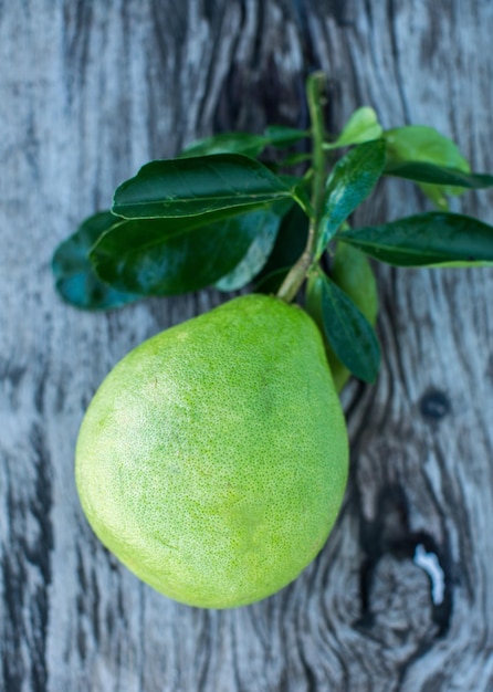 Pomelo met groene bladeren op een houten plank