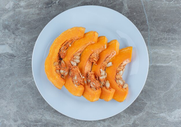 Pompoenschijfjes gerangschikt op een rij, op de marmeren tafel.