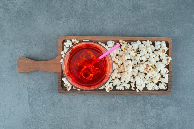 Popcorn en een glas ijskoude drank op een houten bord op blauwe achtergrond. Hoge kwaliteit foto