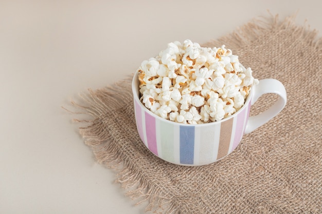 Popcorn in een keramieken kopje op een stuk jute.