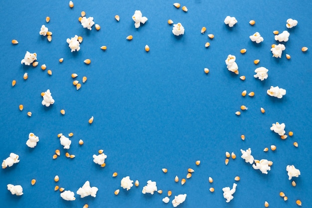 Popcorn op blauwe achtergrond met kopie ruimte in het midden