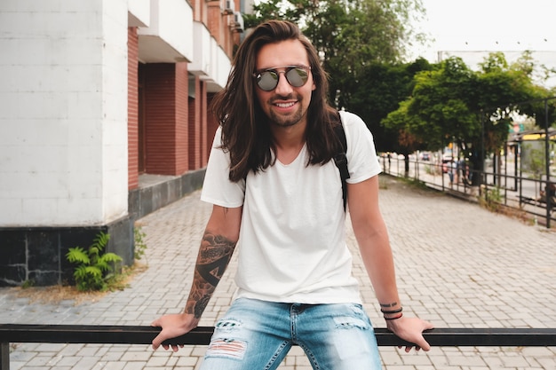 Portret aantrekkelijke man met zonnebril op stedelijke scène glimlachen