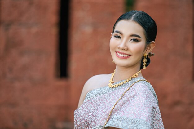 Portret Aziatische charmante vrouw die prachtige typische Thaise kledingsidentiteitscultuur van Thailand draagt in oude tempel of beroemde plaats met gracieus pose