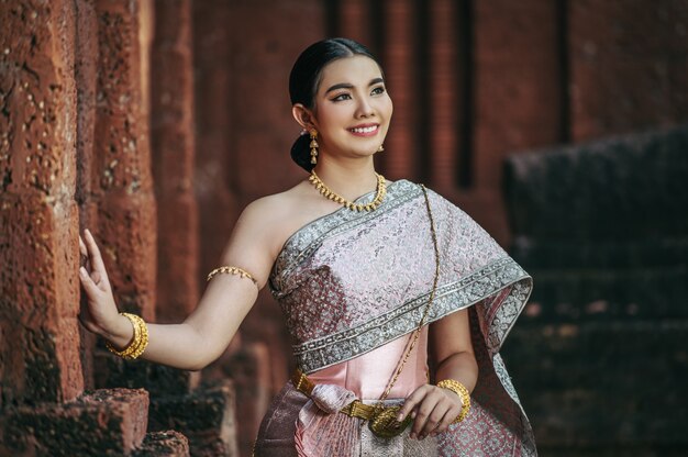 Portret Aziatische charmante vrouw die prachtige typische Thaise kledingsidentiteitscultuur van Thailand draagt in oude tempel of beroemde plaats met gracieus pose