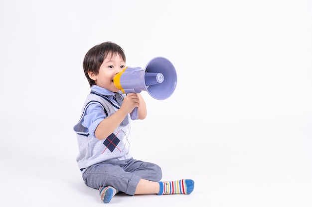 Portret Aziatische jongetje zitten en glimlachen met geluk en vreugdevolle spelen met megafoon