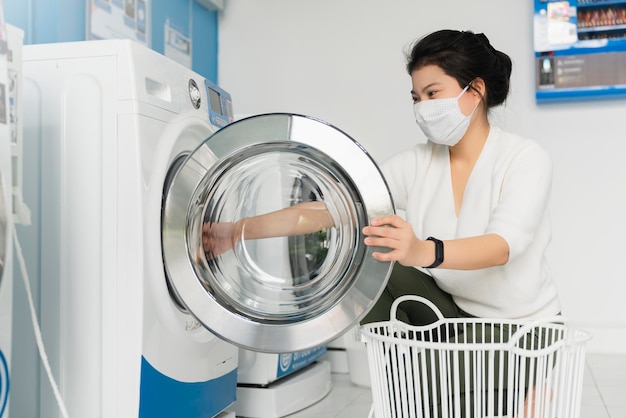 Portret aziatische vrouw draagt een virusbeschermend masker bij de verspreiding van covid19 wassen in blauwe kleur interieur waswinkel in condoiminuim stad nieuwe normale levensstijl