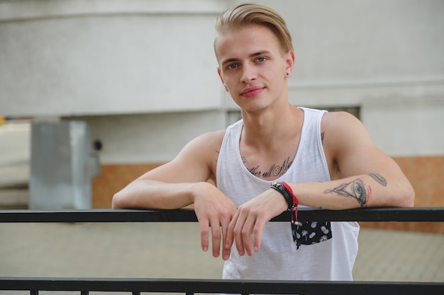 Portret blonde hipster jongen met tatoeages en stijlvol haar