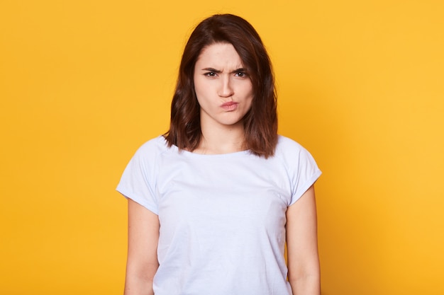 Portret dat van boze jonge vrouw, over geel fronst