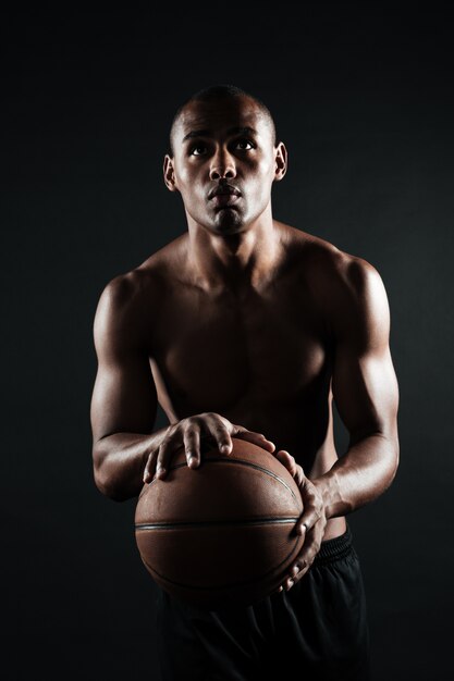 Portret dat van jonge Afro-Amerikaanse basketbalspeler, bal voorbereidingen treft te werpen