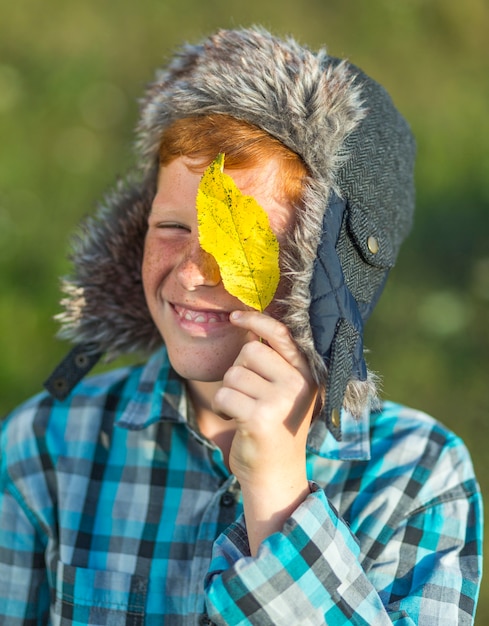 Portret dat van jonge jongen een geel verlof houdt