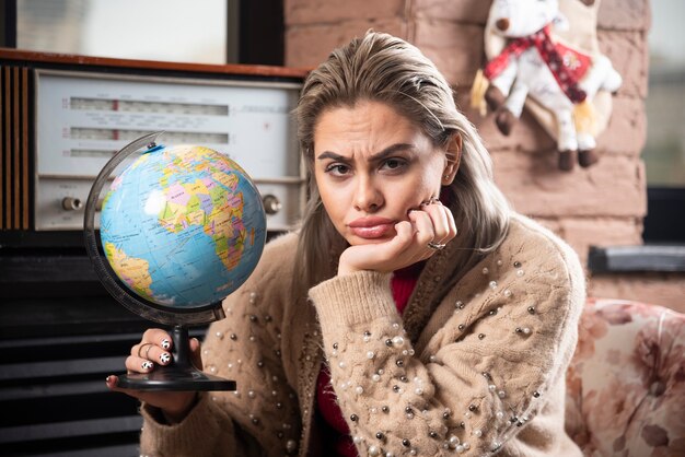 Portret dat van mooie dame een wereldbol houdt