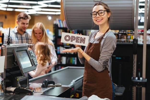 Portret die van gelukkige vrouwenkassier open teken houden