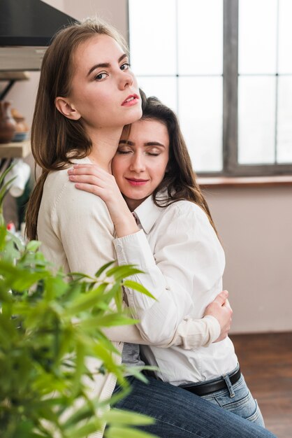 Portret die van lesbische vrouw haar meisje omhelzen die camera bekijken