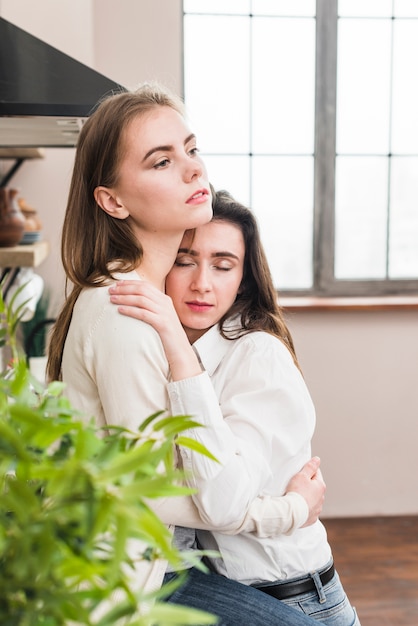 Portret die van lesbische vrouw haar meisje omhelzen die weg eruit zien