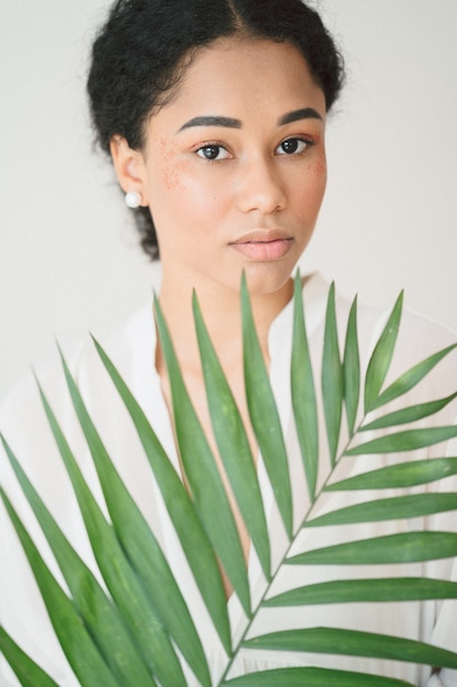 Portret die van mooie dame bij ruimte en palmtak in lange witte kleding bevinden zich houden