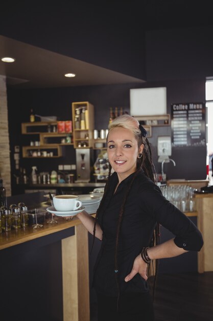 Portret die van serveerster zich met kop van koffie bevinden