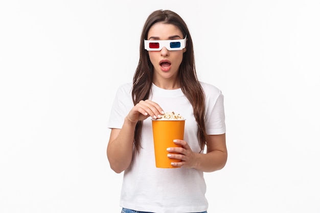 portret expressieve jonge vrouw die popcorn eet en een 3D-bril draagt