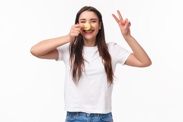 portret expressieve jonge vrouw met smakelijke twee macarons over de ogen