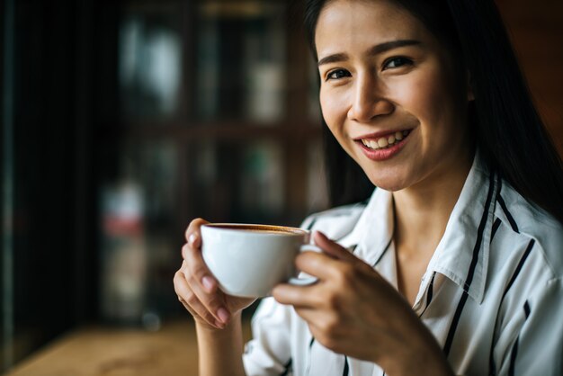 Portret het Aziatische vrouw glimlachen ontspant in de koffie van de koffiewinkel