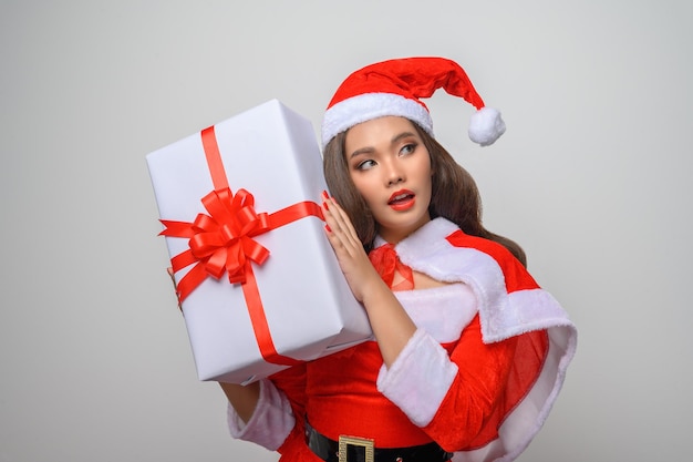 Portret jonge mooie aziatische vrouw in rood kerstmankostuum, glimlach en geschenkdoos in de hand houdend