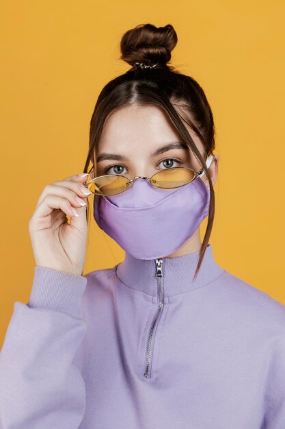 Portret jonge vrouw die zonnebril en masker draagt