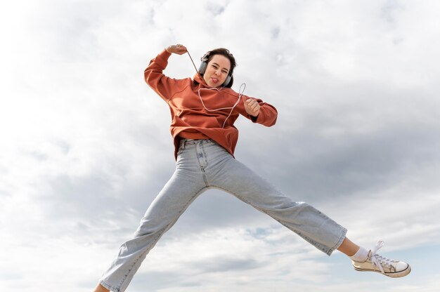 Portret jonge vrouw met koptelefoon springen