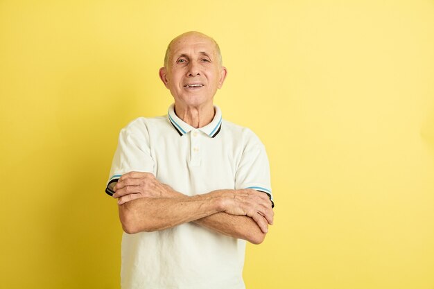 Portret Kaukasische senior man geïsoleerd op gele studio