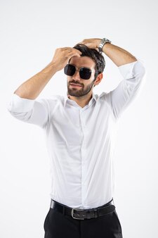 Portret knappe blanke man met zwarte bril, zonnebril, staande kapsel en kijken naar de camera geschoten in een studio met het licht op een witte achtergrond.