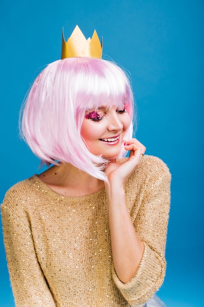 Portret modieuze blije jonge vrouw met gesneden roze haar. lachend met gesloten ogen, make-up met roze tinsels, geluk, feest, nieuwjaar, verjaardag, carnaval vieren.