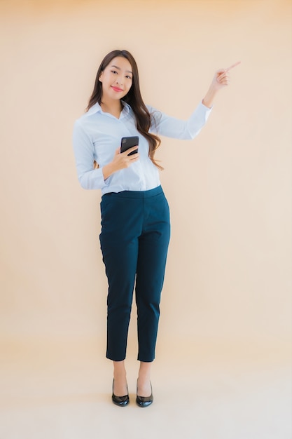 Portret mooie jonge Aziatische bedrijfsvrouw met slimme mobiele telefoon en koffiekop