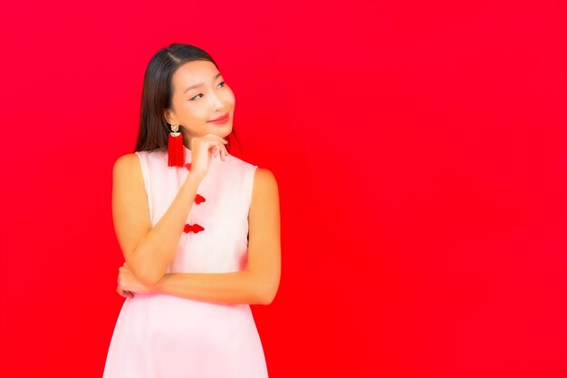 Portret mooie jonge aziatische vrouw draagt chinees nieuwjaarskleding op rode muur