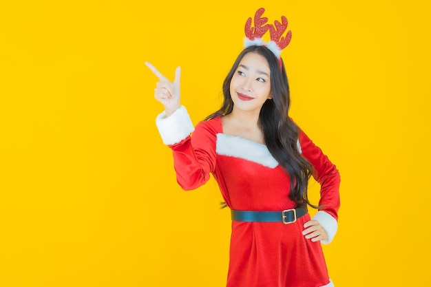 Portret mooie jonge aziatische vrouw draagt kerstkostuum met actie op geel