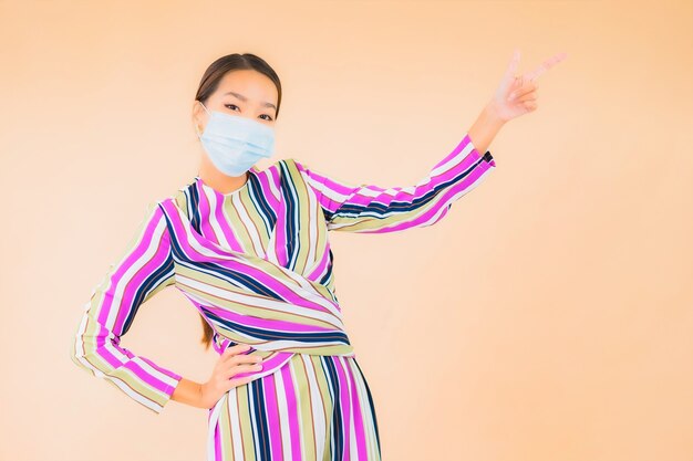 Portret mooie jonge aziatische vrouw draagt ?? masker voor bescherming van het coronavirus of covid19 op kleur