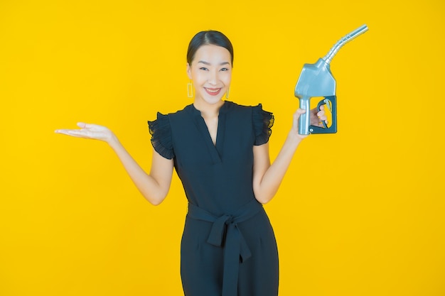 Portret mooie jonge aziatische vrouw feul benzinepomp op geel