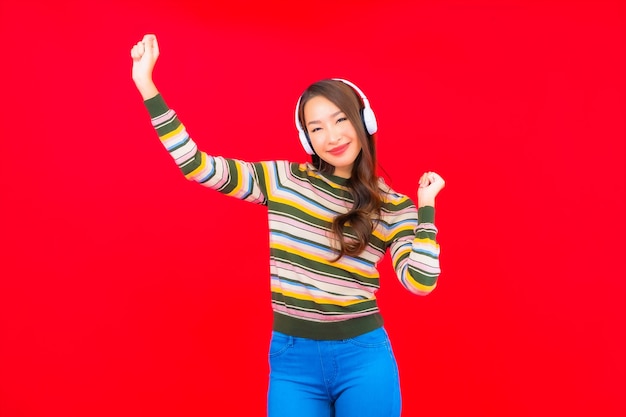 Portret mooie jonge Aziatische vrouw gebruik slimme mobiele telefoon met koptelefoon om naar muziek te luisteren
