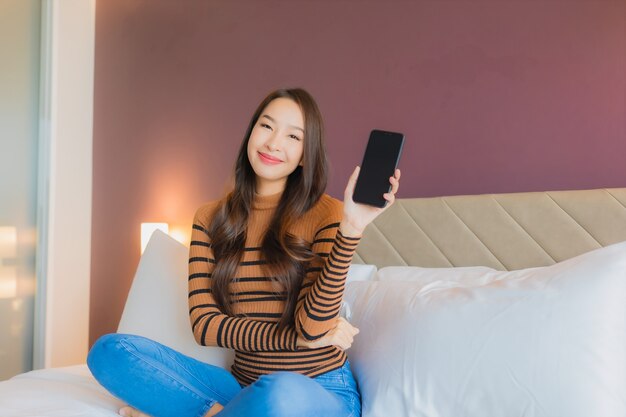 Portret mooie jonge Aziatische vrouw gebruik slimme mobiele telefoon op bed