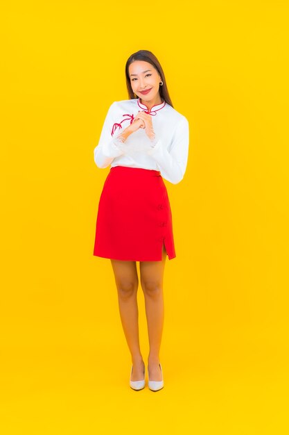 Portret mooie jonge Aziatische vrouw glimlach in actie op geel on