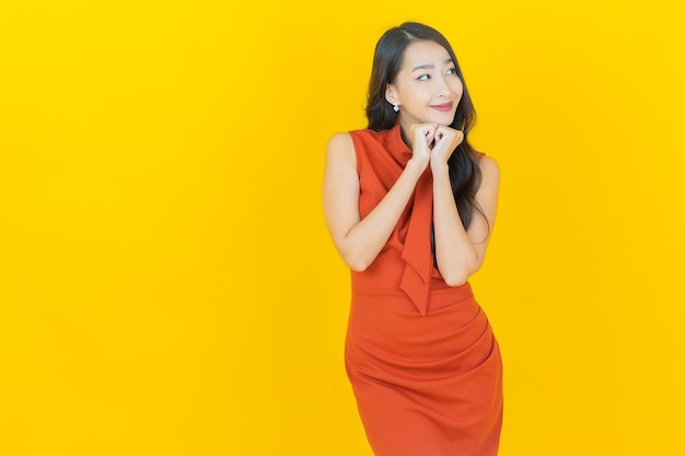 Portret mooie jonge aziatische vrouw glimlach met actie op geel