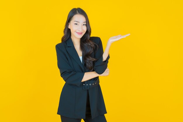 Portret mooie jonge Aziatische vrouw glimlach met actie op geel